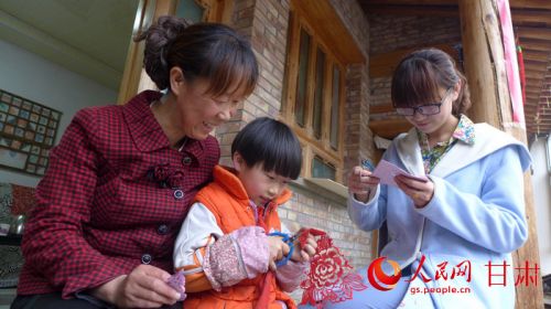 剪纸传承人李淑兰给女儿和孙女传授剪纸技艺。（肖长禄摄）