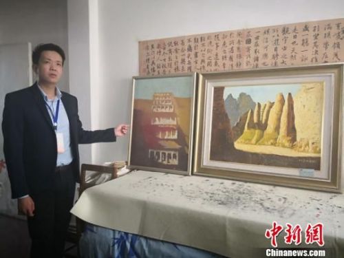 图为牛浩东介绍他的绘画代表作品《敦煌印象》与《黄河石林》。　崔琳 摄