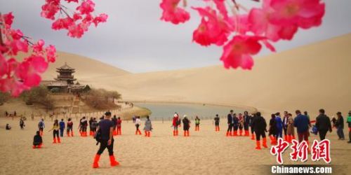 甘肃敦煌月牙泉畔柳绿花红游客酣畅春日沙海