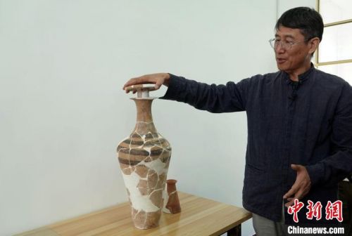 韩建业教授介绍南佐遗址发掘出土的一件独具特色彩陶器——带盖塞(防止酒类液体等挥发)的小口细颈平底瓶。　<a target='_blank'  data-cke-saved-href='/' href='/'>中新社</a>记者 孙自法 摄