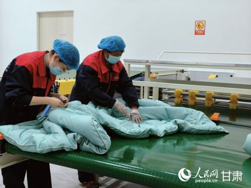 工作人员整理刚刚制作好的艾草被。人民网记者 焦隆摄