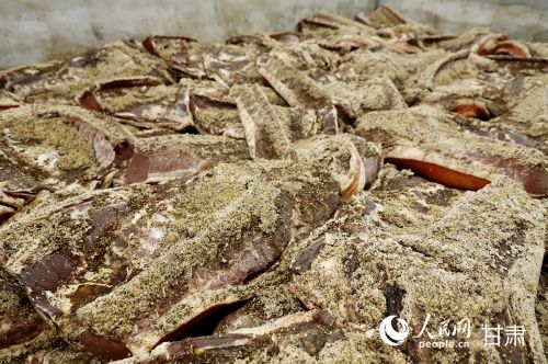 腌制中的陇西腊肉表面密布岩盐、花椒、小茴香等十多种特色香料。人民网记者 焦隆摄