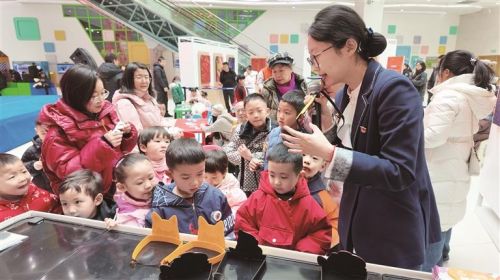 图为讲解员在互动展台前给孩子们解释游戏规则。